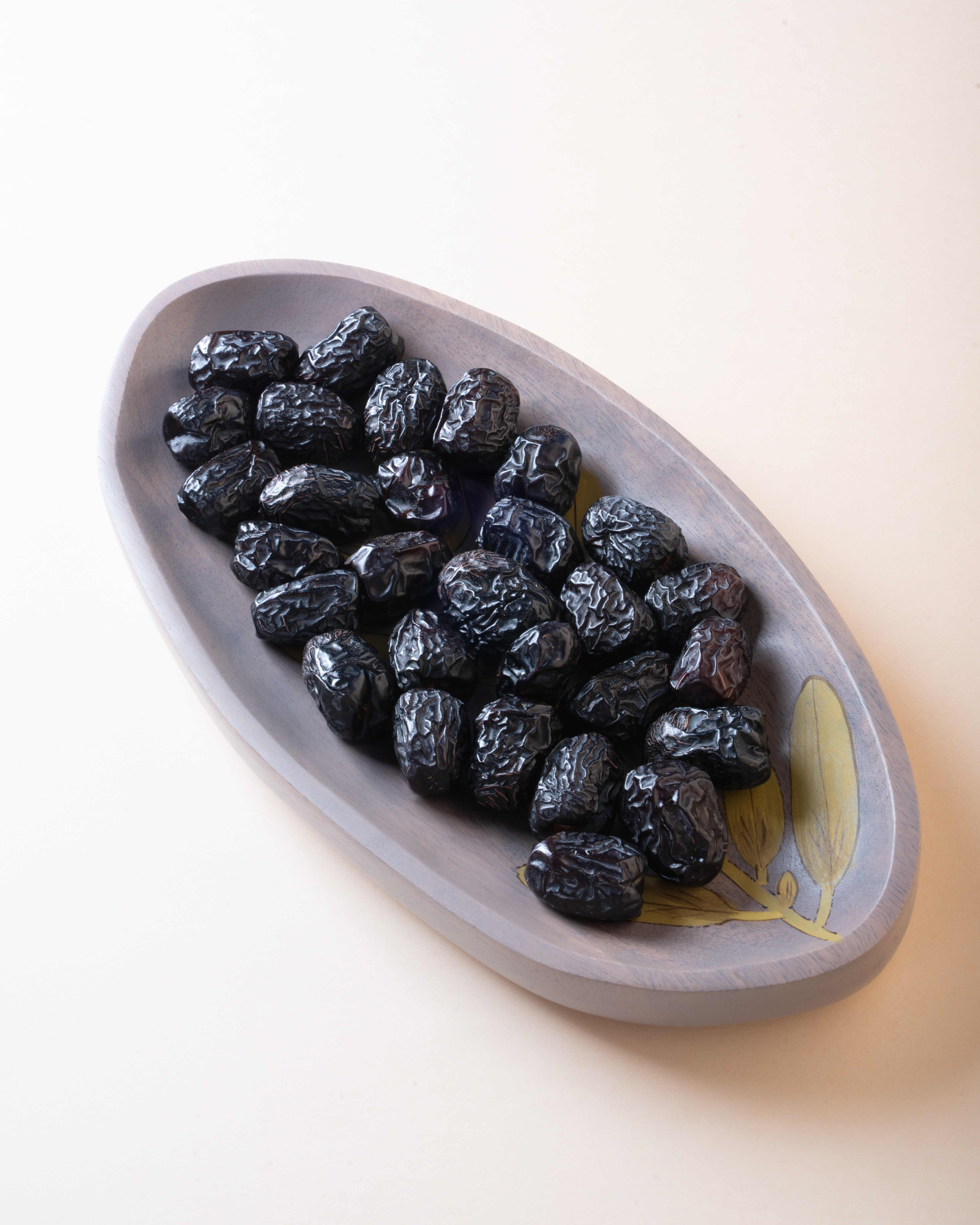 Premium Ajwa dates in a hand-carved wooden bowl
